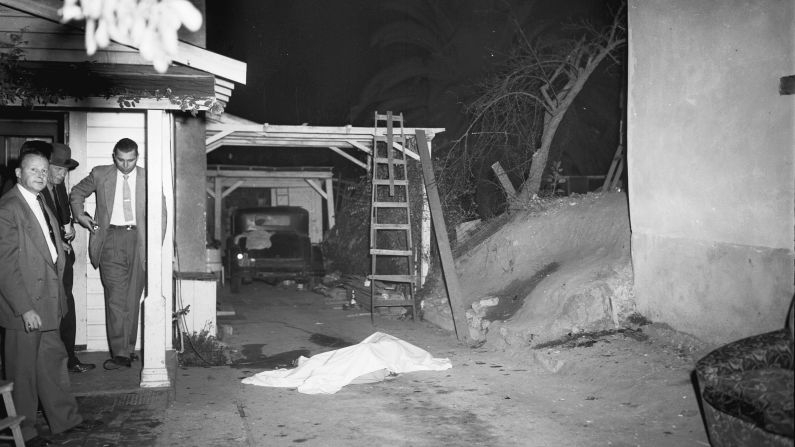 Police officers work at the scene of a gang killing on Halloween night.