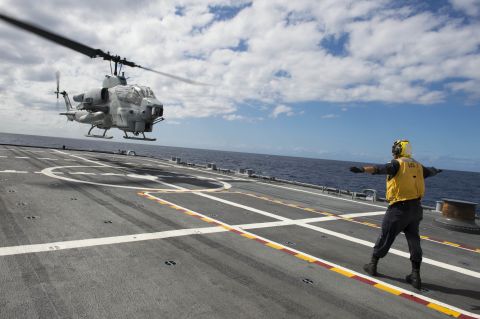 Boatswain's Mate 2nd Class Adam Garnett, from Anchorage, Alaska, signals an AH-1 Cobra helicopter from Marine Air Group (MAG) 24 during deck landing qualification training aboard the USS Fort Worth (LCS 3). The LCSs are designed to support air operations by both helicopters and helicopter drones.