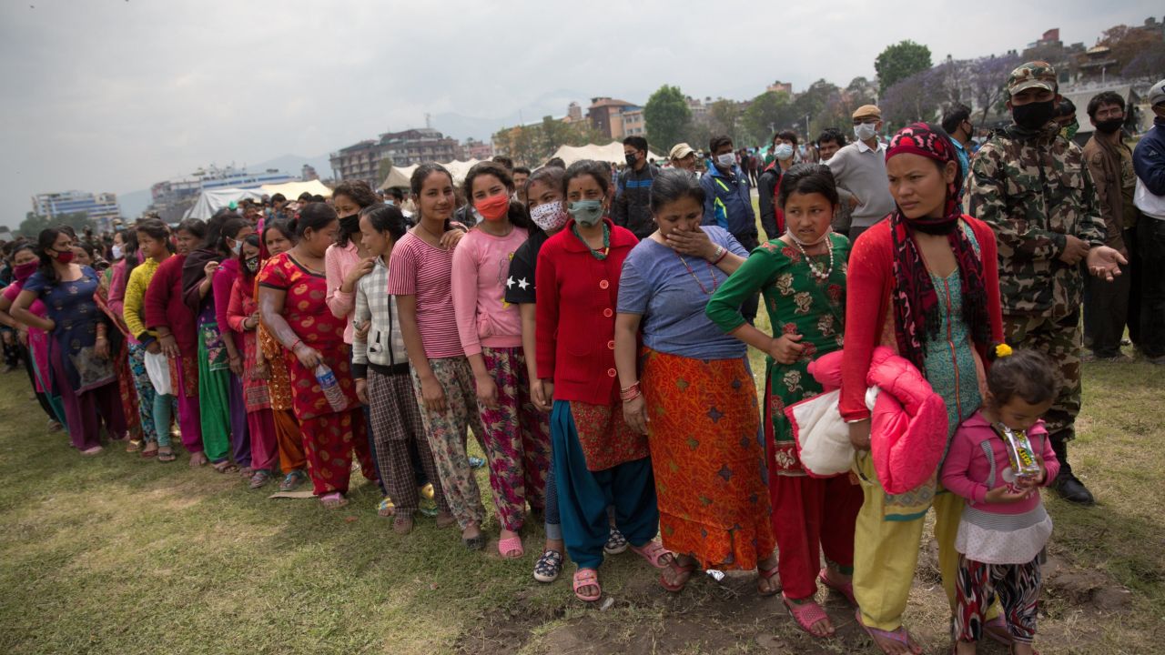 Nepalese women and children wait in line to receive food distributed by a non-government organization in the center of Kathmandu 