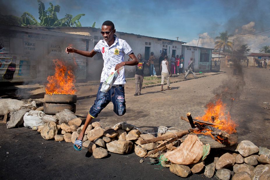 A civilian jumps over a barricade erected by residents to protect themselves from police in Bujumbura on Thursday, May 14.