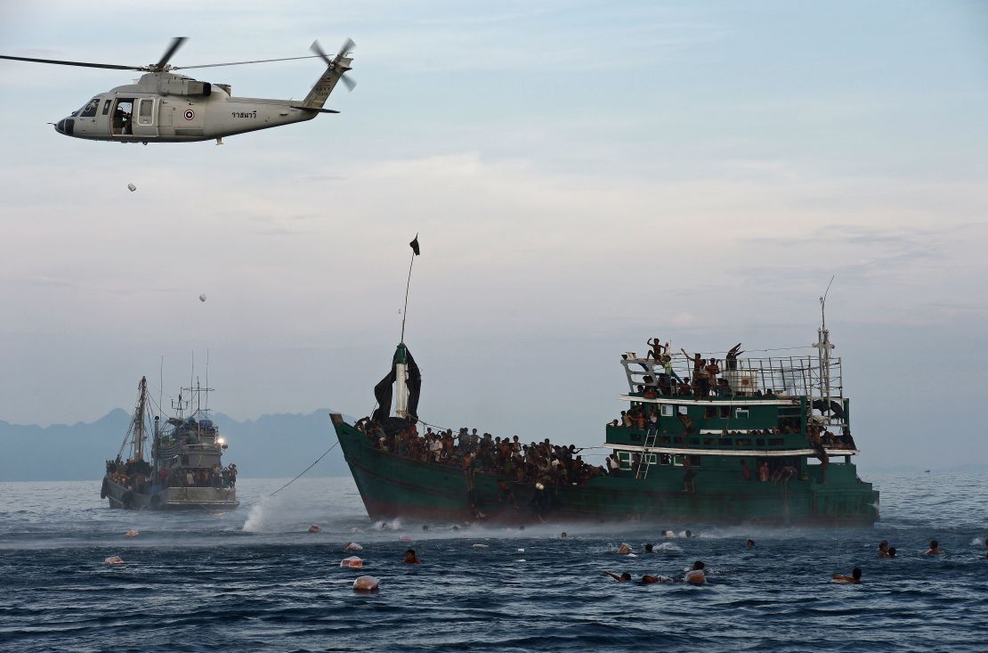 Rohingya migrants swim to collect food supplies dropped by a Thai helicopter. 