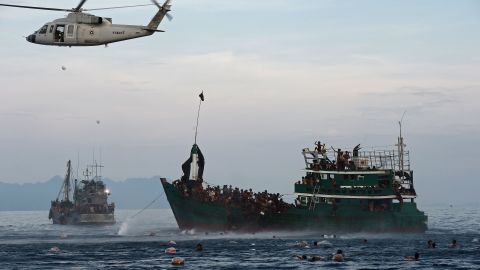 Rohingya migrants swim to collect food supplies dropped by a Thai army helicopter in the Andaman Sea.