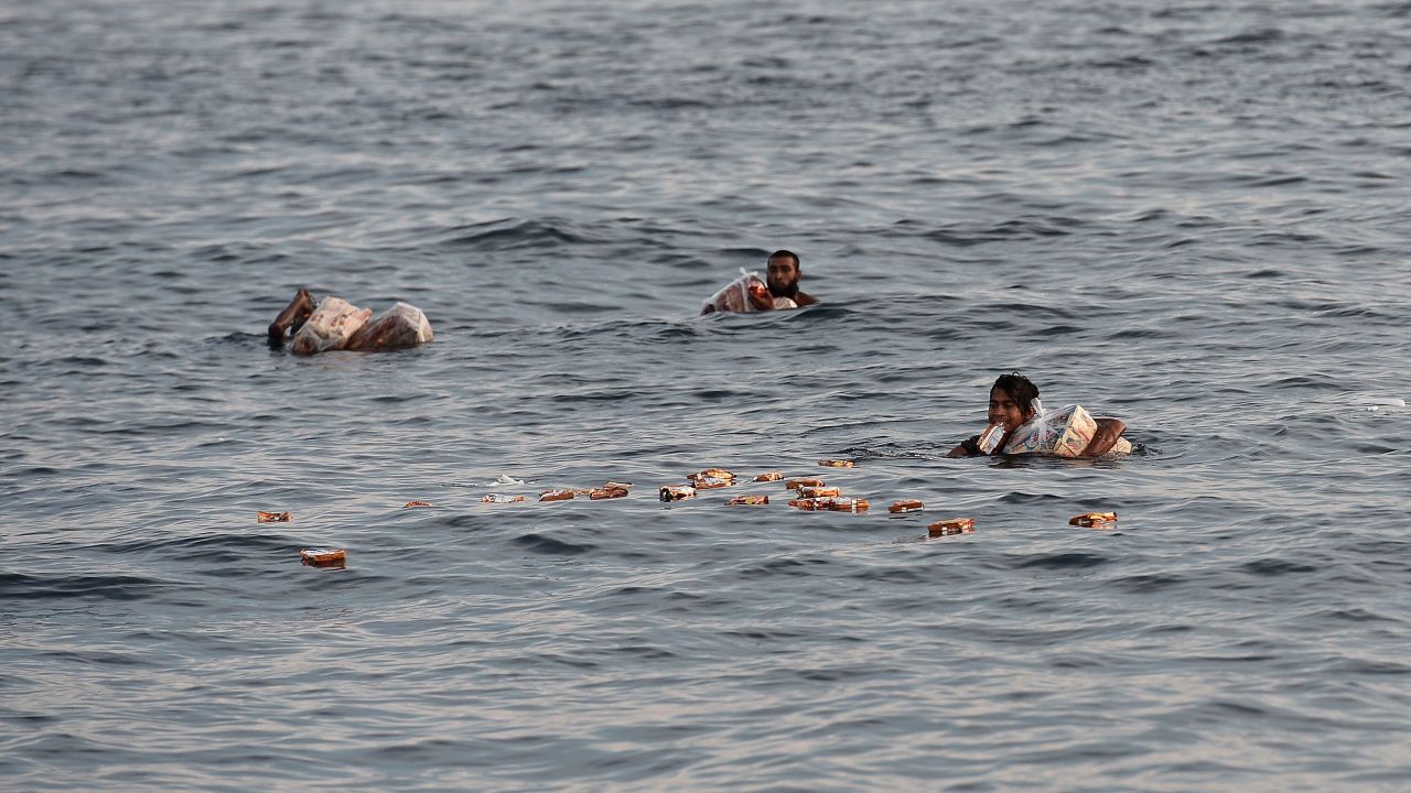 Rohingya migrants collect food supplies.