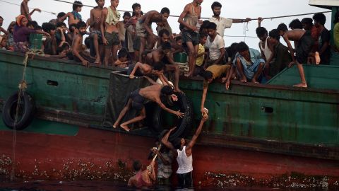 Rohingya migrants on a boat drifting in the Andaman Sea pass food supplies dropped by a Thai army helicopter to others.