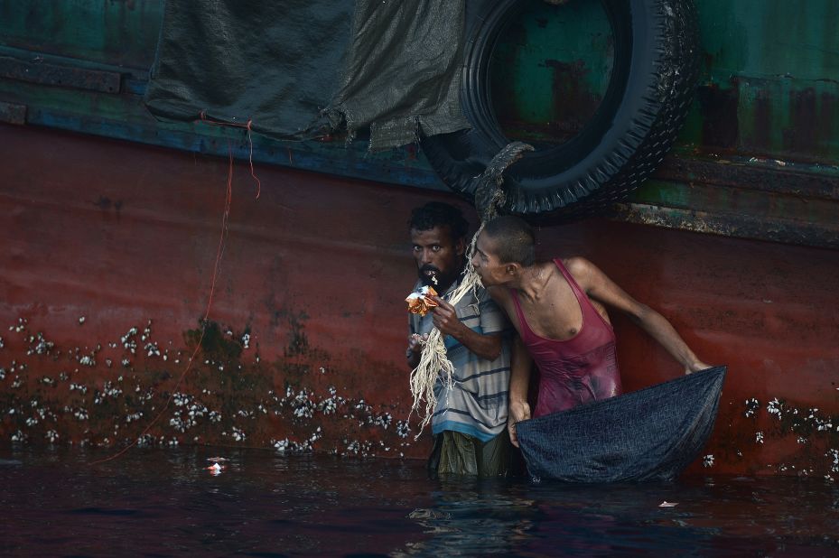 A Rohingya migrant eats food dropped by a Thai army helicopter after he swam to collect the supplies at sea. Malaysia, meanwhile, is processing more than 1,000 recently arrived migrants.