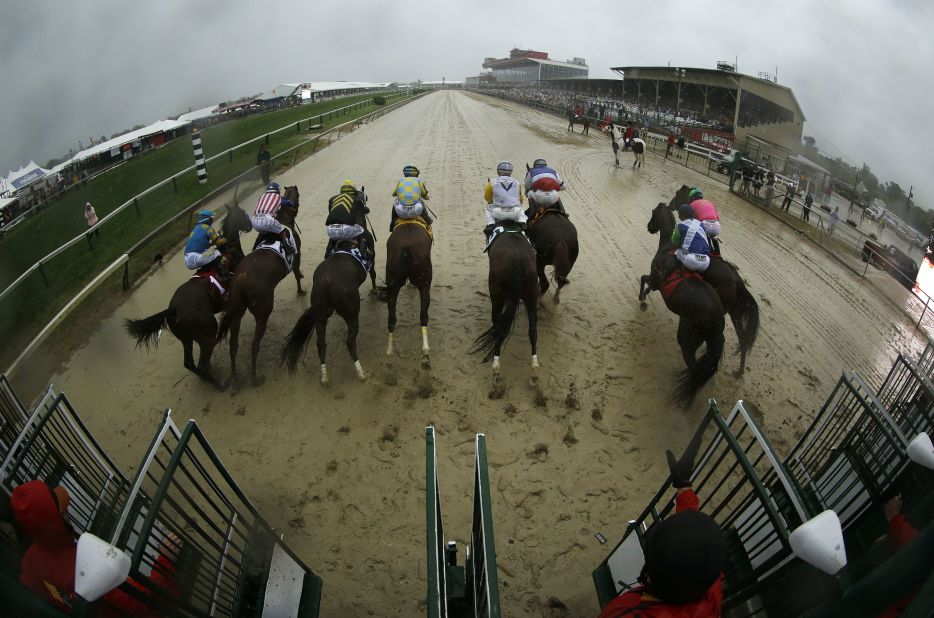 The horses leave the starting gate in the post-storm muck.