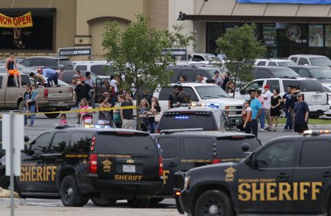 People in Waco, Texas, stand near the parking lot of a Twin Peaks restaurant where nine people were killed in a shooting on Sunday, May 17. At least 18 people were hospitalized as well after a melee between rival biker gangs.