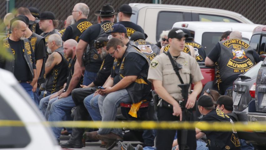 A McLennan County deputy stands guard near a group of bikers in the parking near where the shooting took place. 