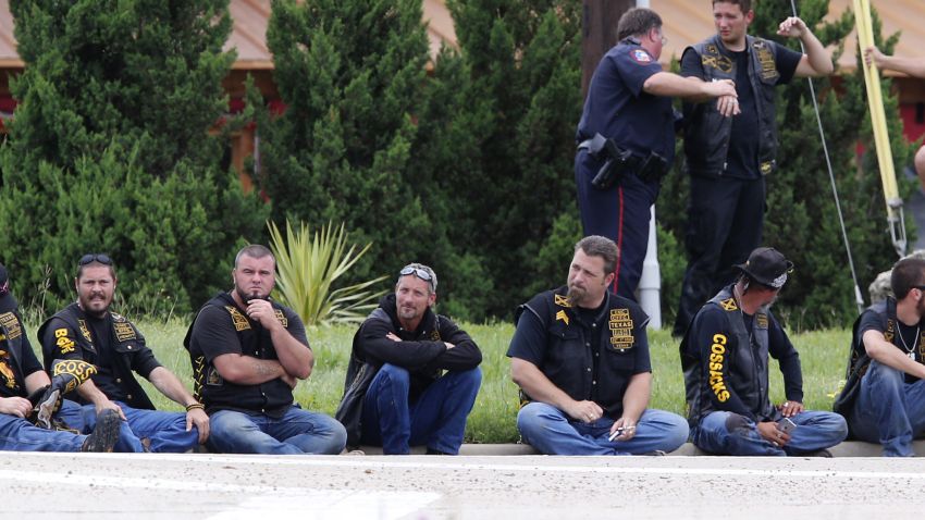 Bikers wait in a line as law enforcement officers investigate the shooting.
