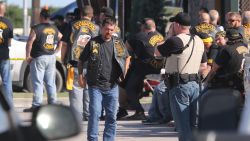 People stand as officers investigate a shooting in the parking lot of the Twin Peaks restaurant Sunday, May 17, 2015, in Waco, Texas. Authorities say that the shootout victims were members of rival biker gangs that had gathered for a meeting. (AP Photo/Jerry Larson)