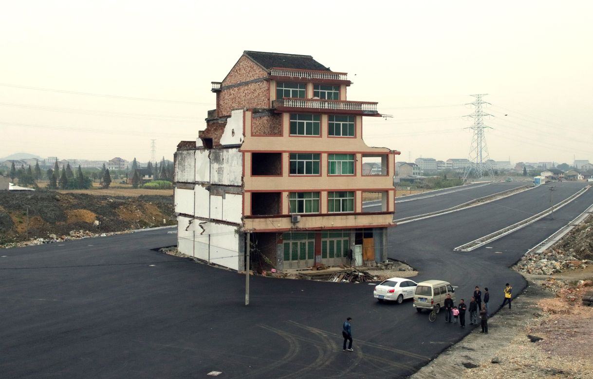 A half-demolished apartment building stands isolated in the middle of a newly-built road on November 22, 2012. Luo Baogen, 67, a duck farmer, and his 65-year-old wife refused to move out from their home in eastern China's Zhejiang province, waging a four-year long battle with the local government over a compensation plan. 