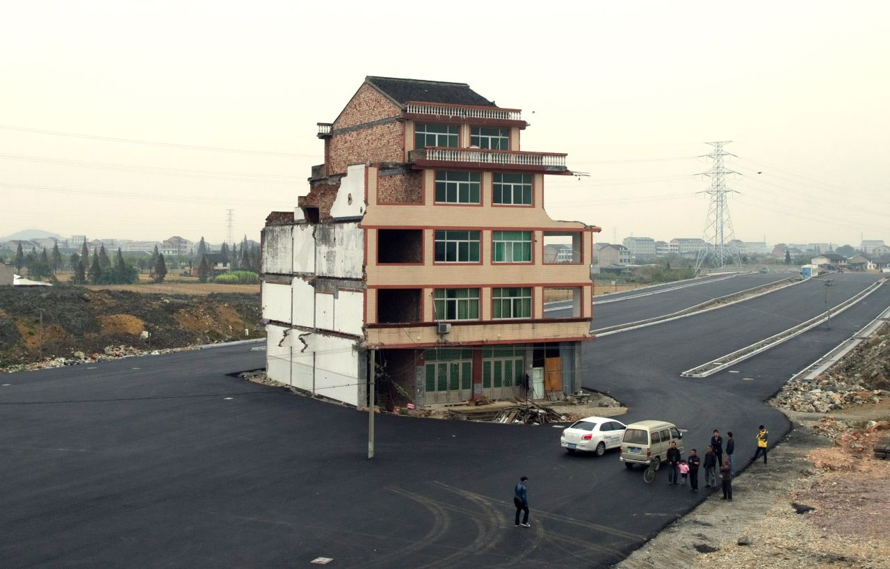 A half-demolished apartment building stands isolated in the middle of a newly-built road on November 22, 2012. Luo Baogen, 67, a duck farmer, and his 65-year-old wife refused to move out from their home in eastern China's Zhejiang province, waging a four-year long battle with the local government over a compensation plan.