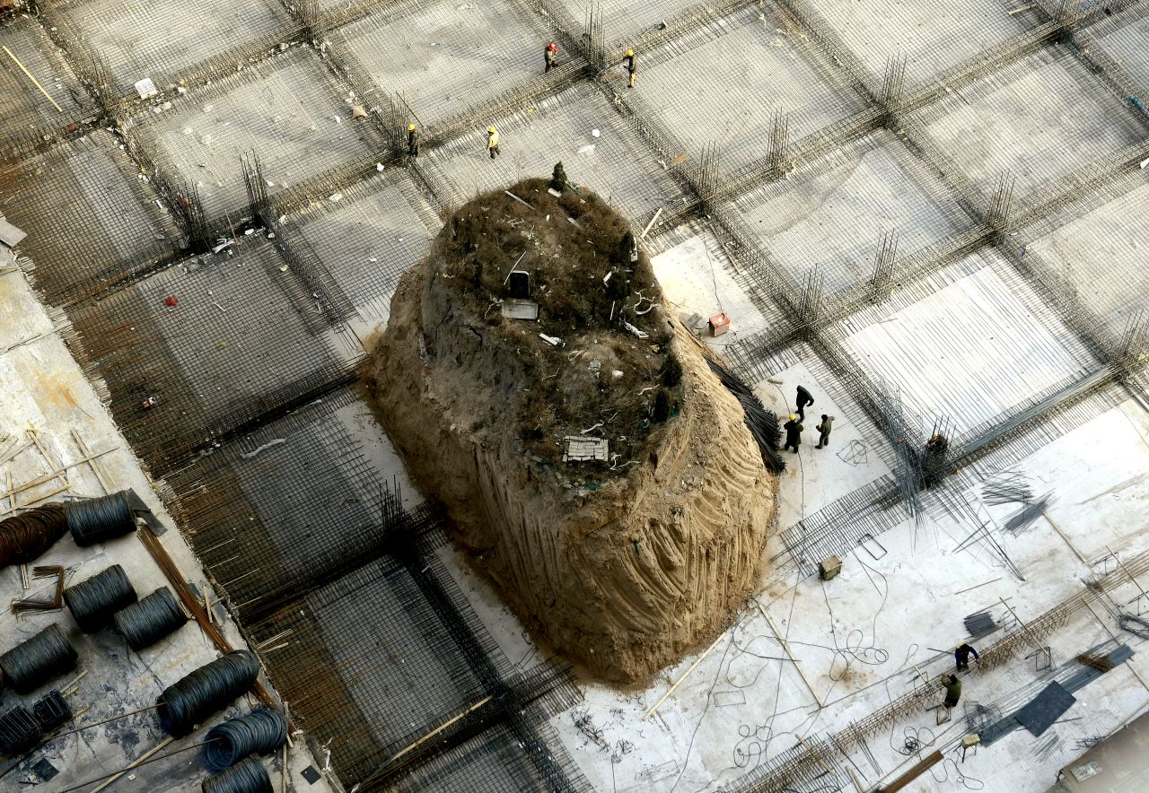 This picture taken on December 6, 2012 shows Chinese workers building around a grave on a 10 meter-high mound at a construction site in a village near Taiyuan, in north China's Shanxi province.
