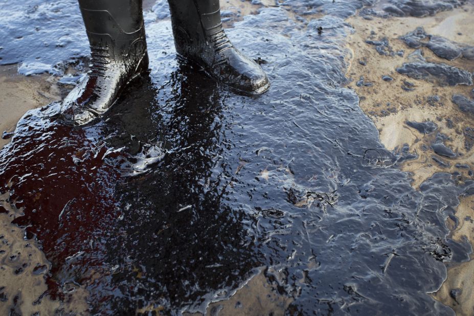 Oil surrounds the feet of local resident Morgan Miller as he patrols the beach for affected wildlife on Tuesday, May 19.