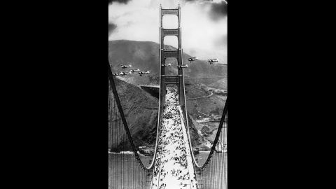 Military biplanes fly between the towers of the bridge as pedestrians walk across the 4,200-foot span during opening ceremonies on May 27, 1937. 