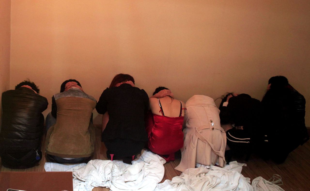 This picture taken on February 9, 2014 shows workers crouching by a wall during a police raid on an entertainment center in Dongguan. An exposé by China's state broadcaster on rampant prostitution in the country's 'sex capital' Dongguan triggered a huge police operation.