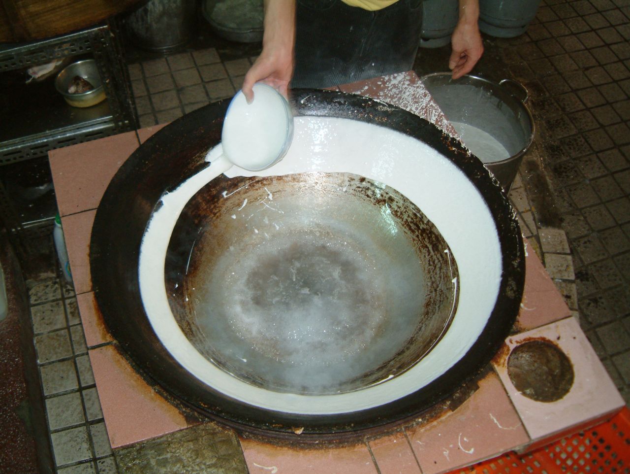Painting the wok with rice slurry to make ding bian cuo.