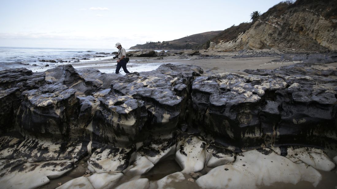 A member of the Bureau of Land Management walks past rocks covered in oil on May 21.