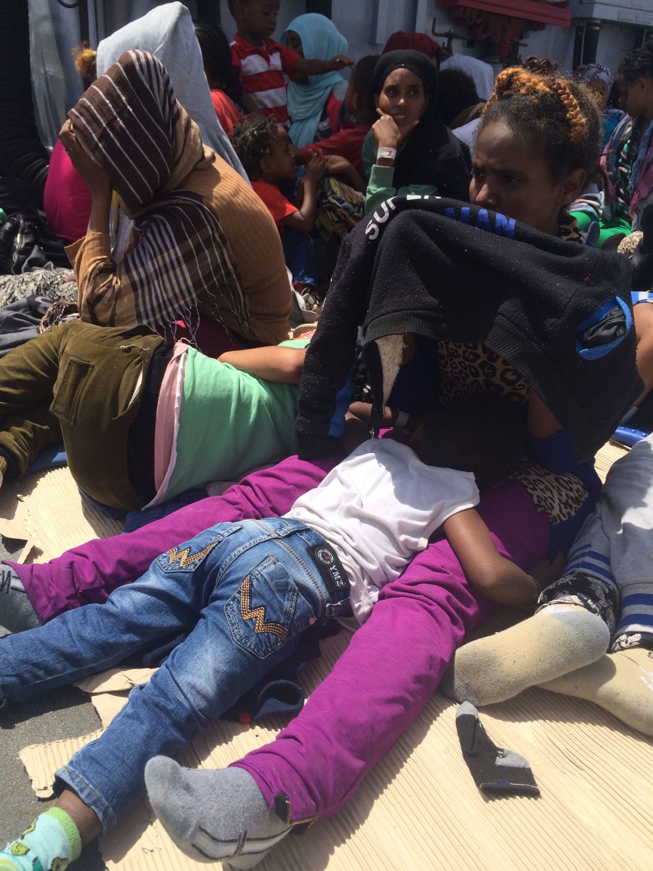 A woman shields her five-year-old child from the intense Mediterranean sun onboard the Sfinge.