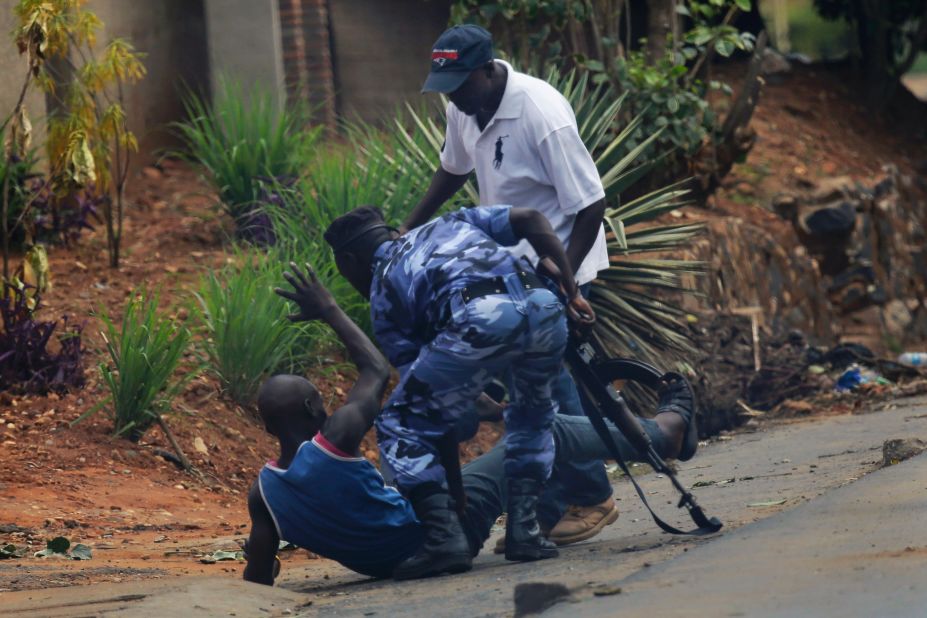 A police officer and a plainclothes member of the Intelligence Services kick a protester in Bujumbura on May 20.