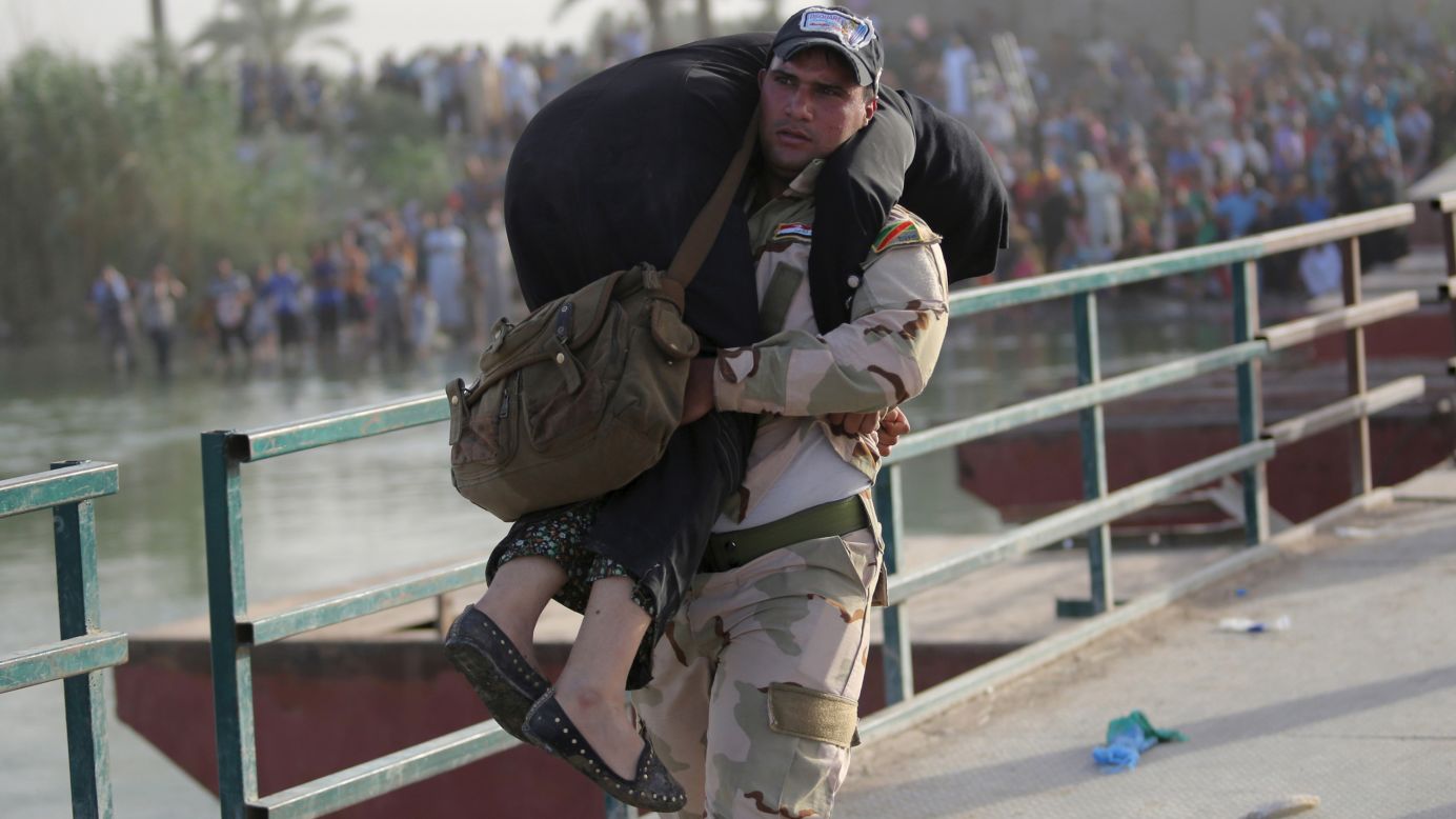 An Iraqi soldier helps a displaced woman cross a bridge on the outskirts of Baghdad, Iraq, on Tuesday, May 19. The ISIS militant group <a href="http://www.cnn.com/2015/05/17/asia/isis-ramadi/index.html" target="_blank">recently took control of the nearby city of Ramadi, </a>the largest city in western Iraq.