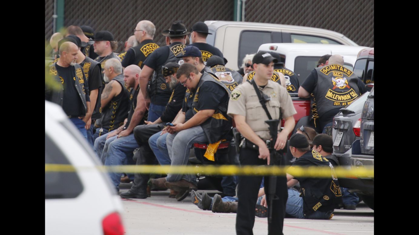 A McLennan County deputy stands guard near a group of bikers in Waco, Texas, after <a href="http://www.cnn.com/2015/05/17/us/gallery/waco-shooting-twin-peaks/index.html" target="_blank">a fight between rival gangs</a> left at least nine people dead on Sunday, May 17.