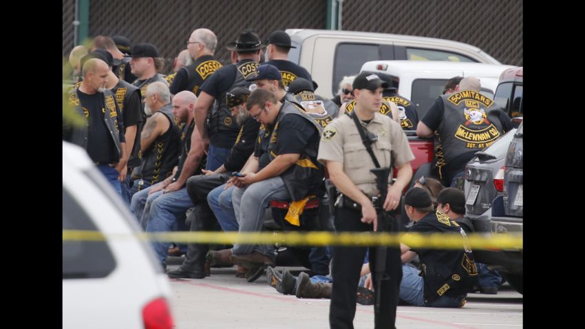 A McLennan County deputy stands guard near a group of bikers in the parking lot of a Twin Peaks restaurant Sunday, May 17, 2015, in Waco, Texas. Waco Police Sgt. W. Patrick Swanton told KWTX-TV there were "multiple victims" after gunfire erupted between rival biker gangs at the restaurant. 