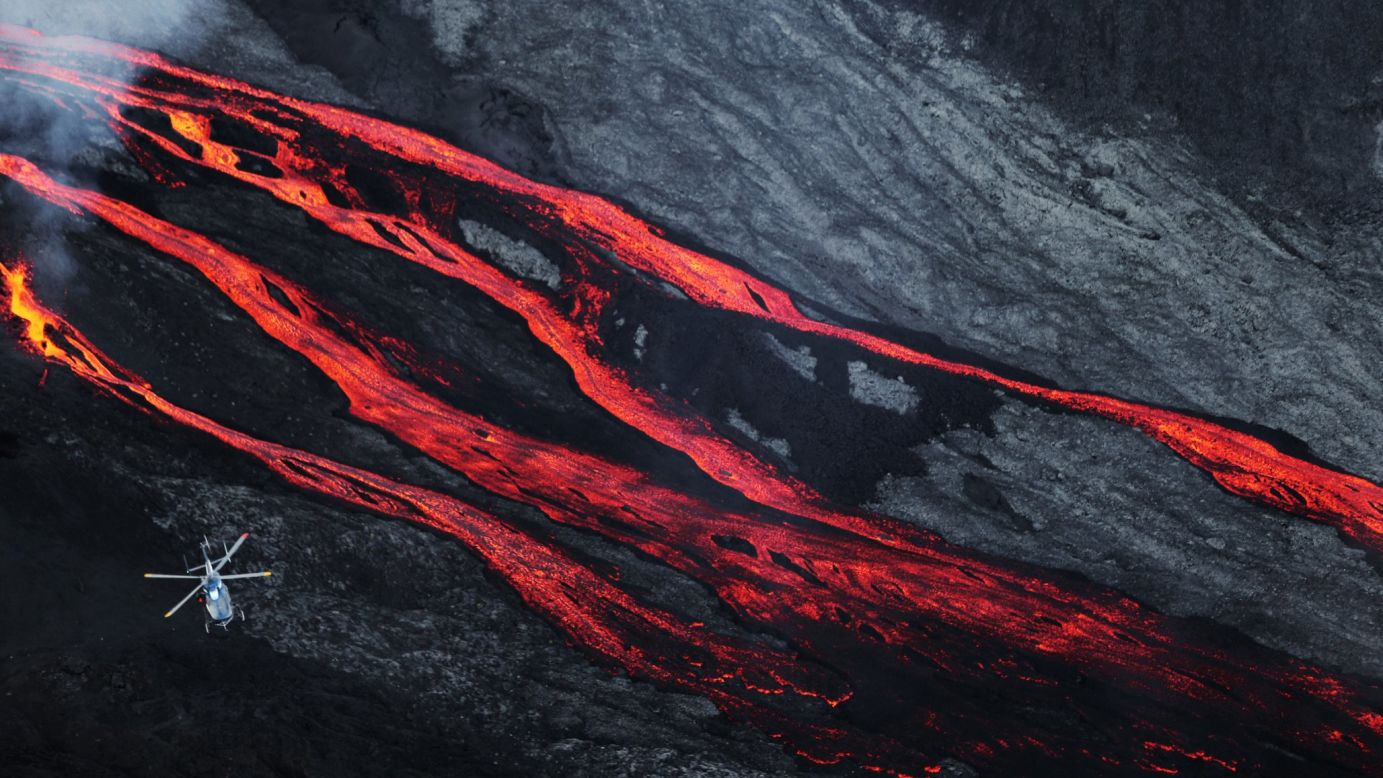 A helicopter flies overhead as lava flows out of the Piton de la Fournaise volcano on Sunday, May 17. The volcano is on the French island of Reunion in the Indian Ocean.