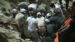 White Helmets assist in removing the body of a Syrian from the rubble of buildings following a reported barrel bomb attack by government forces on the Qadi Askar district of the northern Syrian city of Aleppo on May 20, 2015. 