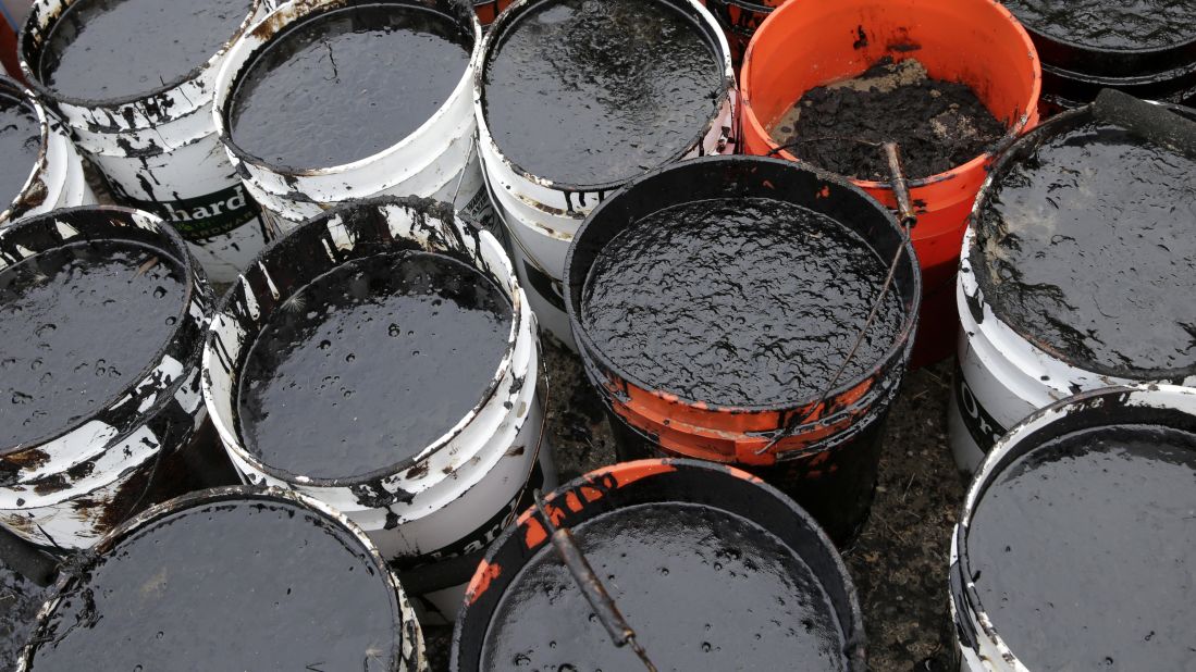Plastic buckets are filled with oil collected from the beach on May 21.
