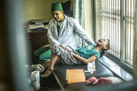 Dr. Bibek Banskota holds Maya Gurung as she screams in pain during a session to measure her leg. The photo was taken from a reflection in a mirror, so the image is reversed.