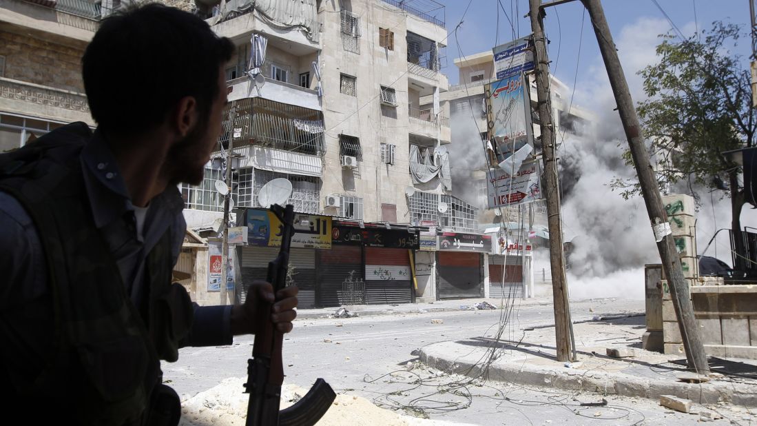 A Free Syrian Army fighter runs for cover as a Syrian Army tank shell hits a building across the street during clashes in the Salaheddine neighborhood of central Aleppo on August 17, 2012.