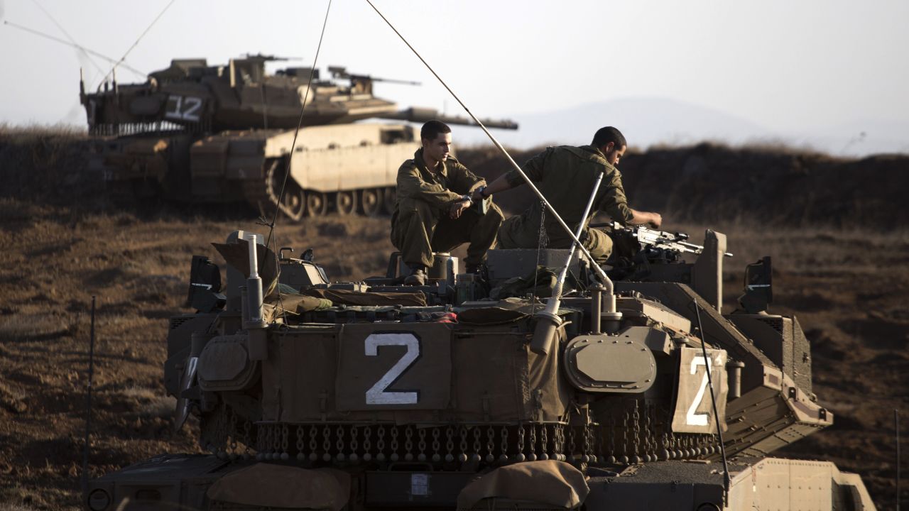 An Israeli tank crew sits on the Golan Heights overlooking the Syrian village of Breqa on November 6, 2012. Israel fired warning shots toward Syria after a mortar shell hit an Israeli military post. It was the first time Israel fired on Syria across the Golan Heights since the 1973 Yom Kippur War.