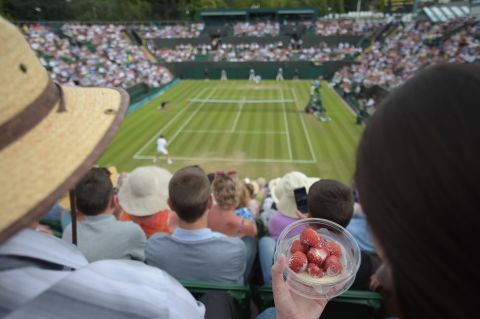 A spectator eats strawberries and cream as she watches Spain's David Ferrer play against Russia's Andrey Kuznetsov during the 2014 event.