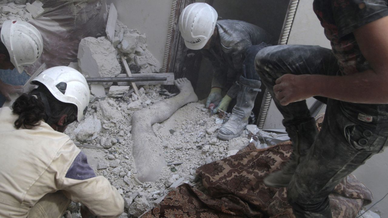 Volunteers remove a dead body from under debris after shelling in Aleppo on August 29, 2014. According to the Syrian Civil Defense, barrel bombs are now the greatest killer of civilians in many parts of Syria. The White Helmets are a humanitarian organization that tries to save lives and offer relief.