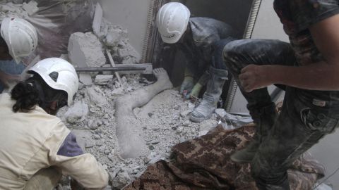 Volunteers remove a dead body from under debris after shelling in Aleppo on August 29, 2014. According to the Syrian Civil Defense, barrel bombs are now the greatest killer of civilians in many parts of Syria. The White Helmets are a humanitarian organization that tries to save lives and offer relief.