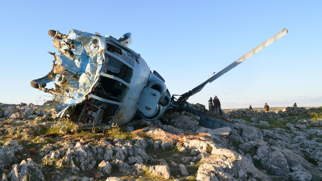 Nusra Front fighters inspect a helicopter belonging to pro-government forces after it crashed in the rebel-held Idlib countryside on March 22, 2015.