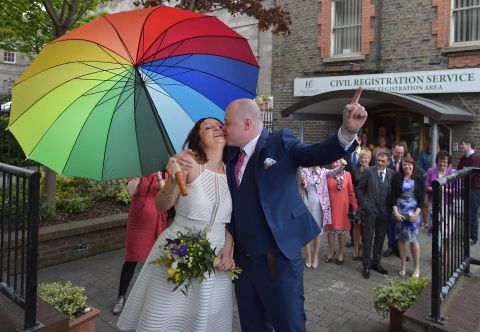 Newly married couple Anne and Vincent Fox kiss in Dublin on Friday, May 22, under a rainbow umbrella, showing their support for the "yes" side in the same-sex marriage referendum.<br />