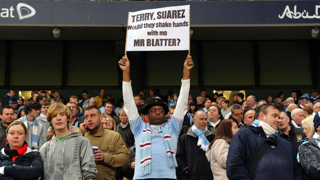 A Manchester City fan displays a banner with a message for FIFA President Sepp Blatter regarding his handling of  allegations of racism in football in 2011. Blatter had earlier suggested that incidents of racism on the pitch could be sorted out with a handshake when a game finished.