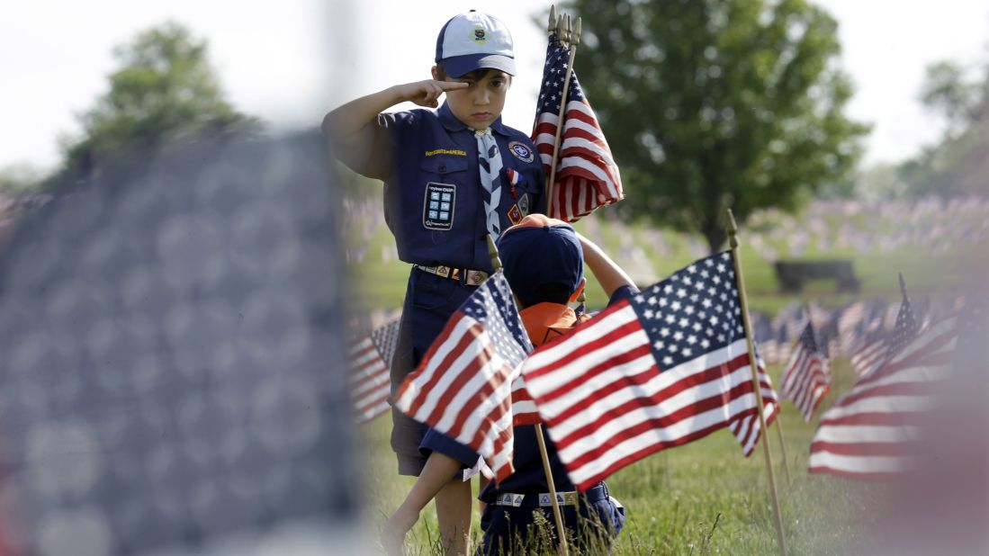 Cub Scout Tristan Swanhart salutes after he placed a flag on a grave at a veterans cemetery in Wrightstown, New Jersey, on Friday, May 22.