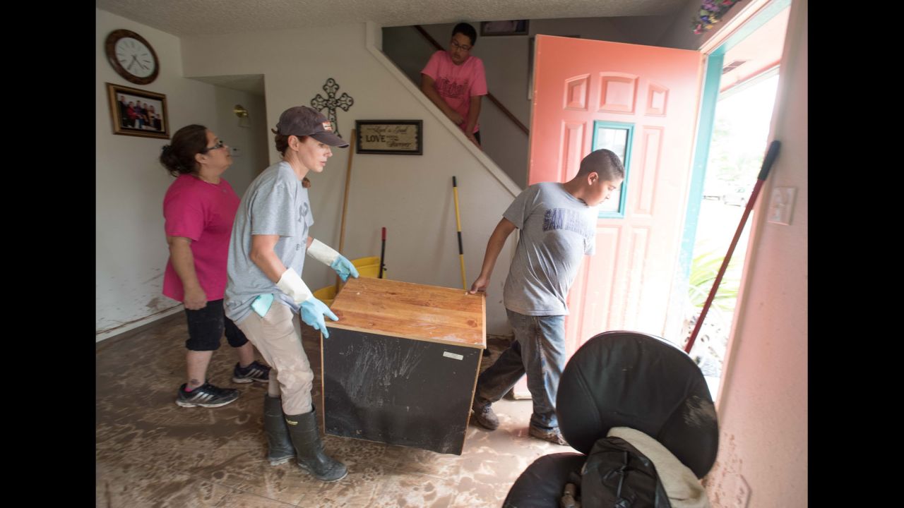 Heather Williams and Jayden Martinez Corpus assist the Villegas family in clearing flood-damaged furniture from their home in San Marcos on May 24.