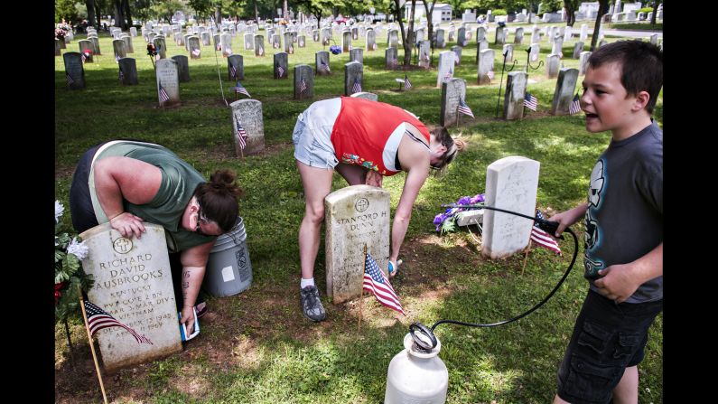 From left, Carla Lawrence, her sister Brandi Burch and her son Gabe Lawrence clean veterans' gravestones at Fairview Cemetery in Bowling Green, Kentucky, on Sunday, May 24. Burch's grandfather, great-grandfather, and great-great-grandfather are all buried at the cemetery.