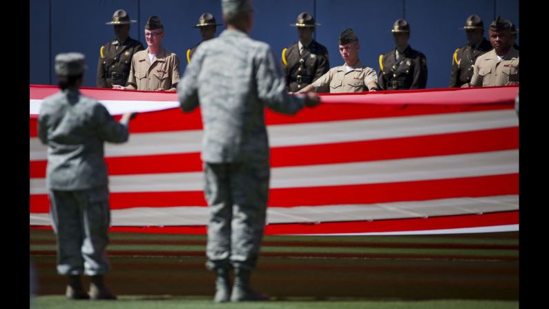 Members of the military stand at attention while unveiling a giant American flag before the start of a Major League Baseball game in Atlanta on Saturday, May 23.