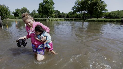 Nayeli Cervantes carries her friend's daughter through the floodwaters outside their Houston apartment on May 26.