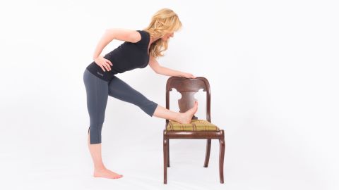 While holding your chair back or desk for balance, place your left foot on the seat of your chair. If necessary, lower your chair height to a safe, comfortable level. Keep your hips squared and your left toes in dorsi flexion (pointing up). Exhale as you flex from your hips — as opposed to rounding your back — to bend forward toward your leg. Hold for three long, deep breaths. Repeat on the other side. 