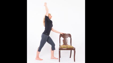 Place your left hand lightly on top of your chair or desk, step your right foot back into a short lunge. Drop your back heel and point your toes out slightly. Bend your front knee to align above your ankle, keeping your back leg straight. Inhale as you lift your right arm up and over your head. Exhale as you side bend to the left. Keep your core activated for balance and avoid arching your lower back. Press the front of your right hip forward to release your right hip flexors. Hold for three long, deep breaths. Repeat on the other side.