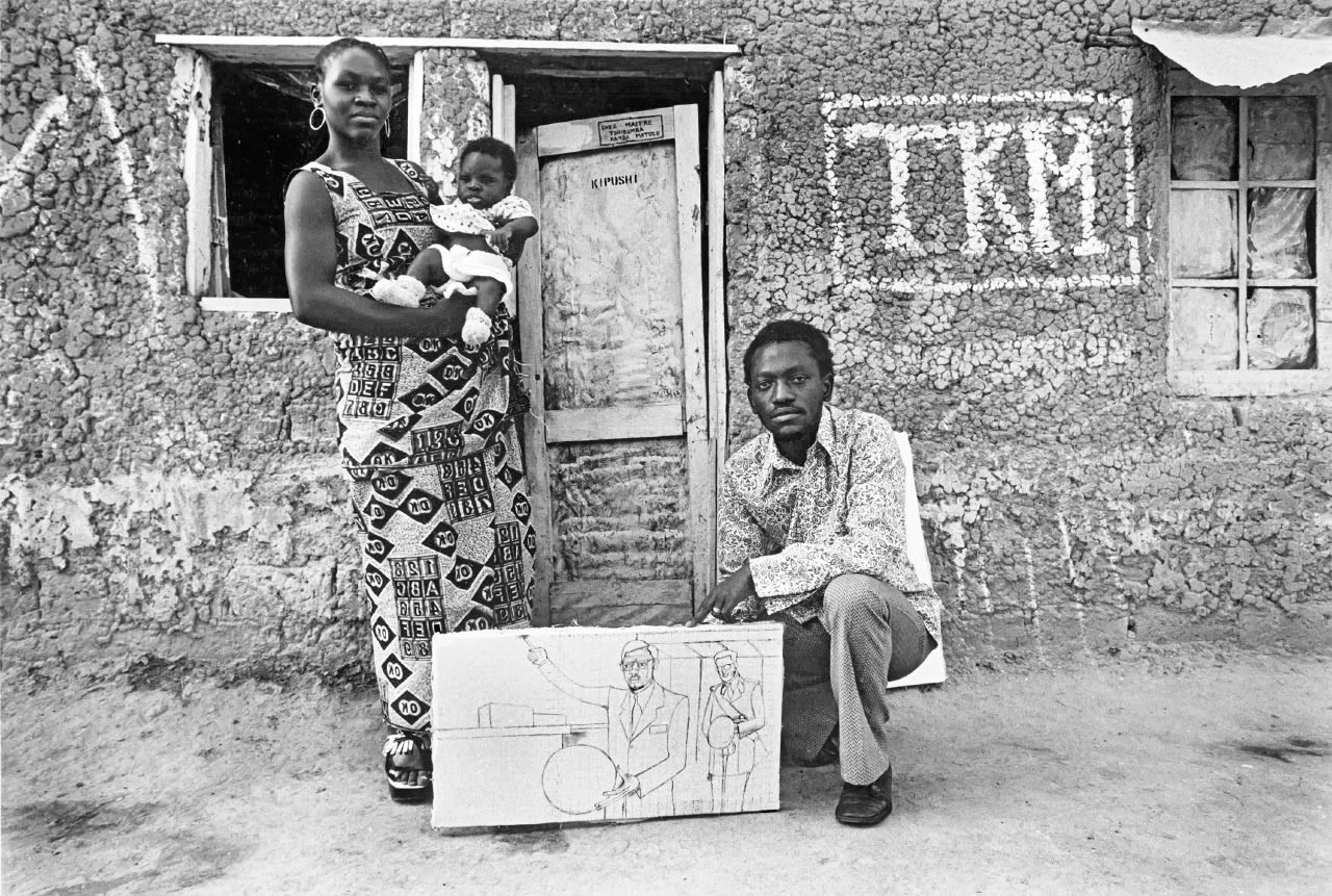 Kanda-Matulu with his family. Here he's holding the unfinished painting of 'Declaration d'Indépendance'.