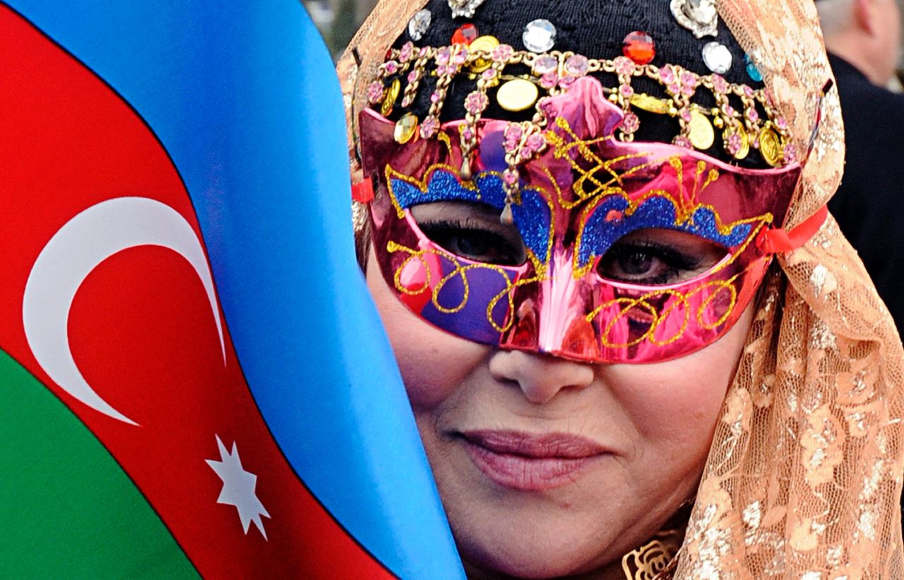 A masked woman holds an Azerbaijani flag during a spring welcome festival in Baku.