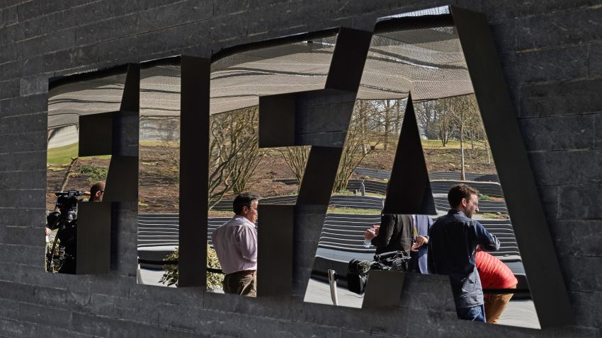 Caption:Member of the media wait next to a logo of the Worlds football governing body, at the FIFA headquarters in Zurich, prior to a press conference of FIFA President Sepp Blatter on March 20, 2015, closing a two-day meeting to decide the dates of the 2022 World Cup in Qatar. AFP PHOTO / MICHAEL BUHOLZER (Photo credit should read MICHAEL BUHOLZER/AFP/Getty Images)
