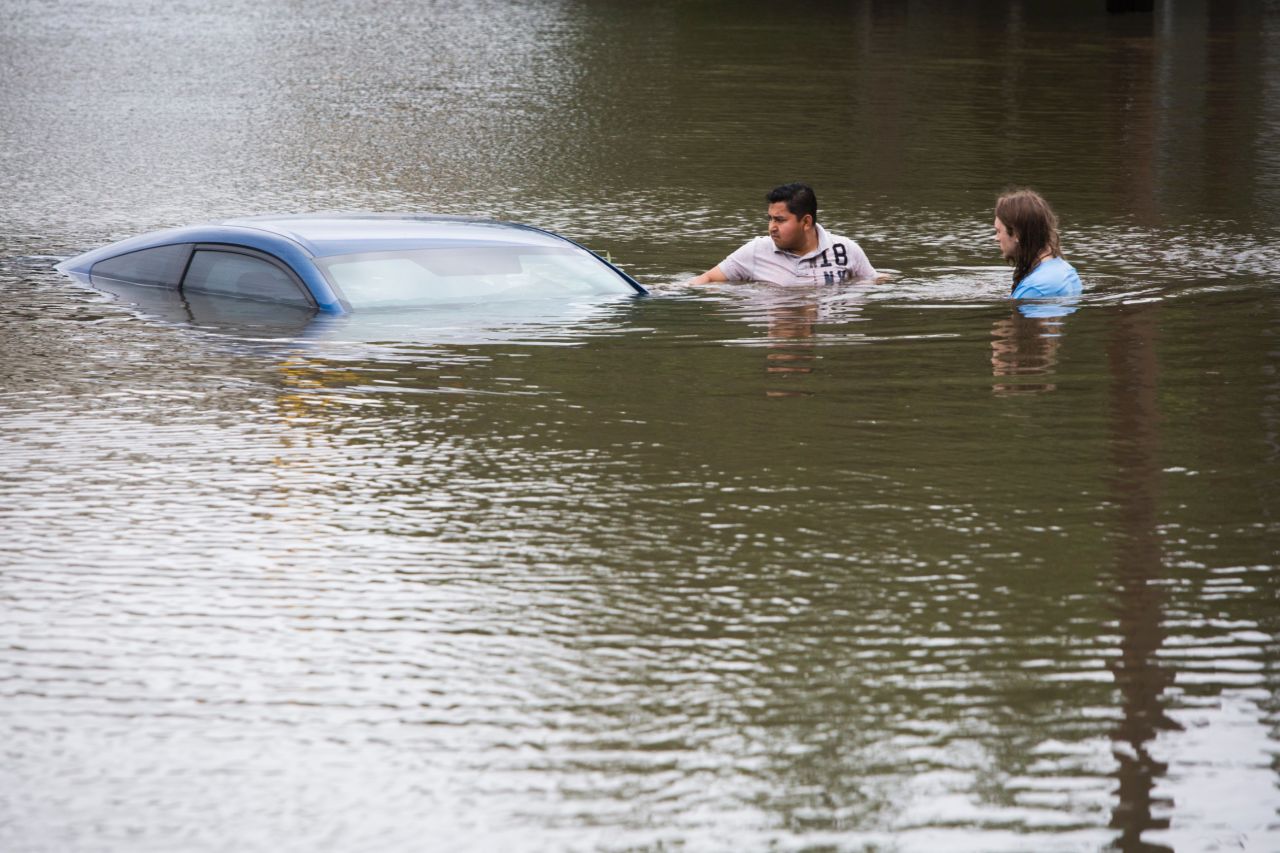 Roberto Salas, left, and Lewis Sternhagen check on a flooded car in Houston on May 26.